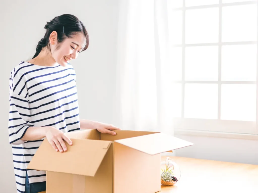 新しい部屋で段ボール空けて片づけする女性